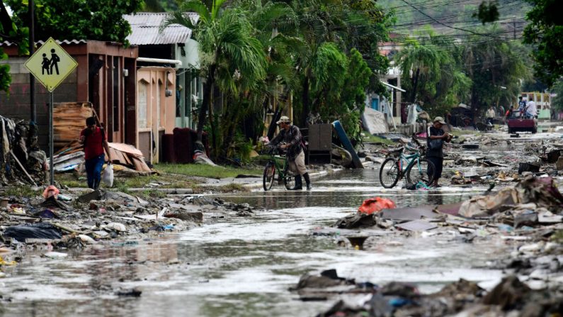 La gente camina por una calle cubierta de barro con escombros causados ​​por las inundaciones del huracán Iota el 21 de noviembre de 2020 en San Pedro Sula, Honduras. (Foto de Yoseph Amaya / Getty Images)