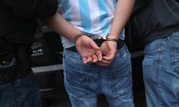 Agentes del ICE de Investigaciones de Seguridad Nacional (HSI) registran a un presunto miembro de la pandilla MS-13 e inmigrante hondureño luego de arrestarlo en su casa en Brentwood, Nueva York, el 29 de marzo de 2018. (John Moore/Getty Images)