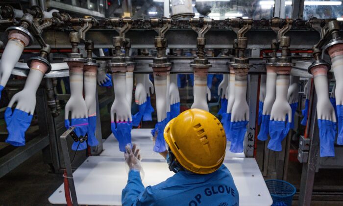 Un trabajador inspecciona guantes desechables en la línea de producción de la fábrica Top Glove, en Shah Alam, en las afueras de Kuala Lumpur, el 26 de agosto de 2020. (Mohd Rasfan/AFP a través de Getty Images)