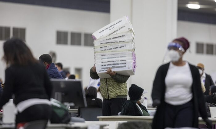 Un trabajador del Departamento de Elecciones de Detroit lleva cajas vacías que se utilizan para organizar las papeletas de voto ausente después de acercarse al final del conteo de votos ausentes en la Junta Central de Conteo en el TCF Center en Detroit, Michigan, el 4 de noviembre de 2020 (Elaine Cromie/Getty Images)
