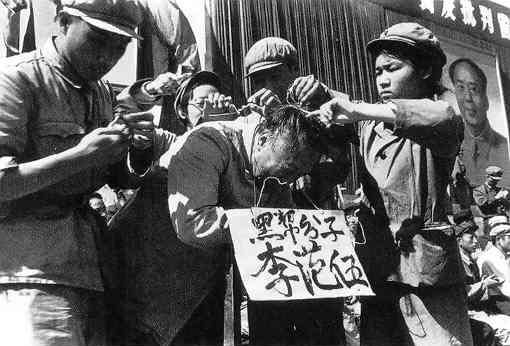 Los dirigentes del Partido Comunista cuelgan un cartel en el cuello de un hombre chino durante la Revolución Cultural en 1966. Las palabras en el cartel dicen el nombre del hombre y lo acusan de ser miembro de la "clase negra". (Dominio publico)