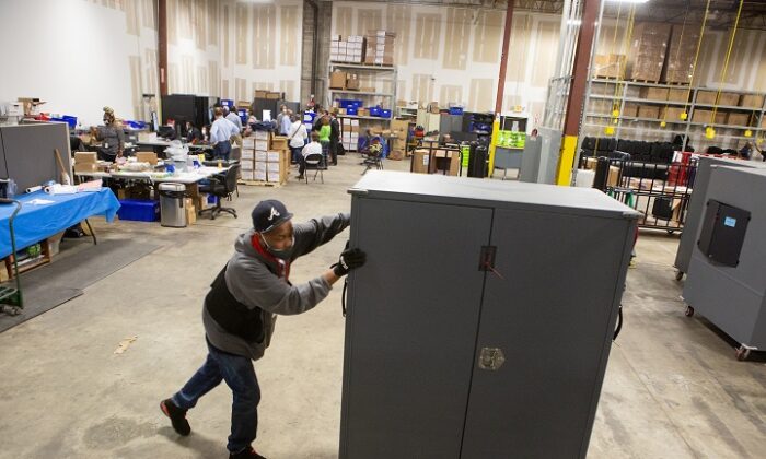 Un empleado del condado de Fulton mueve transportadores de máquinas de votación para ser almacenados en el Centro de Preparación de Elecciones del condado de Fulton en Atlanta, Georgia, el 4 de noviembre de 2020. (Jessica McGowan/Getty Images)