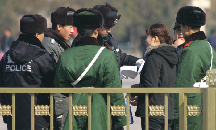 La policía y los guardias paramilitares rodean a una mujer mientras un policía lee su petición en medio de una seguridad reforzada en la Plaza de Tiananmen en Beijing el 6 de marzo de 2007. (FREDERIC J. BROWN/AFP vía Getty Images)