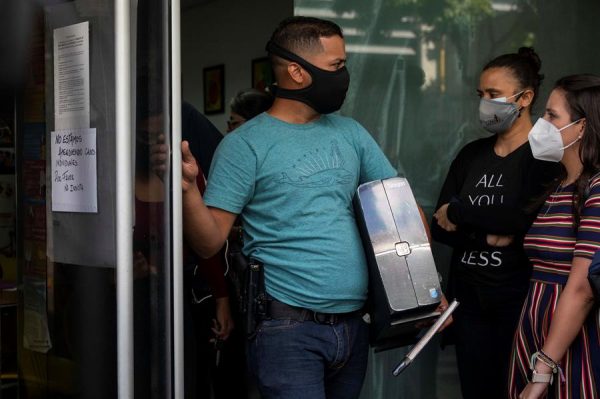 Un agente de las Fuerzas de Acciones Especiales (FAES) de la Policía Nacional Bolivariana saca un ordenador de la sede de la ONG Convite durante un allanamiento, en Caracas (Venezuela), el 15 de diciembre de 2020. EFE/RAYNER PEÑA R