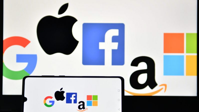 Una foto tomada en Londres el 18 de diciembre de 2020 muestra los logotipos de Google, Apple, Facebook, Amazon y Microsoft en un celular y una pantalla de laptop. (Justin Tallis/AFP a través de Getty Images)