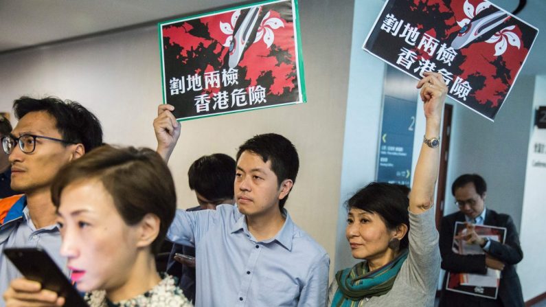 Los legisladores prodemocracia Ted Hui (C) del Partido Demócrata y Claudia Mo (centro R) del Partido Cívico sostienen carteles que dicen "ceder tierras con uso compartido pone a Hong Kong en peligro" en el edificio del Consejo Legislativo en Hong Kong el agosto 3, 2017. (Isaac Lawrence/AFP/Getty Images)
