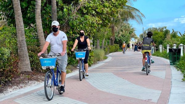 Turistas usan mascarillas mientras andan en bicicleta por la playa en Miami, Florida, el 20 de diciembre de 2020, en medio de la pandemia de covid-19. Foto de DANIEL SLIM / AFP a través de Getty Images)