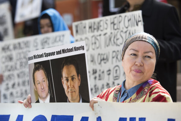 Turnisa Matsedik-Qira, de la Asociación de Uigures de Vancouver, se manifiesta en contra del trato que China da a los uigures mientras sostiene una foto de los canadienses detenidos Michael Spavor y Michael Kovrig frente a una comparecencia ante el tribunal de la directora de finanzas de Huawei, Meng Wanzhou, en la Corte Suprema de B.C. en Vancouver el 8 de mayo de 2019. (Jason Redmond/AFP vía Getty Images)