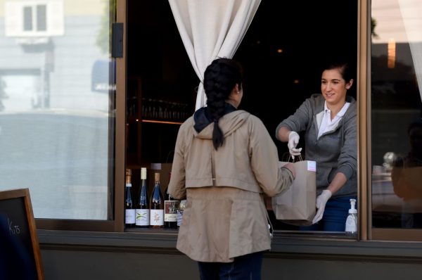 Un empleado del restaurante Atelier Crenn entrega un pedido para llevar a un cliente a través de una ventana en San Francisco, California, el 1 de abril de 2020, durante el brote del covid-19. (Foto de JOSH EDELSON / AFP a través de Getty Images)