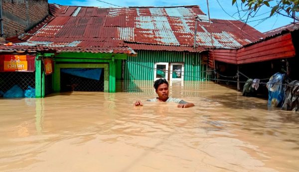 Esta foto tomada el 28 de noviembre de 2020 muestra a un hombre que sale de su casa inundada en Tebing Tinggi, mientras miles de casas se inundaron en el norte de Sumatra (Indonesia) después de que lluvias torrenciales azotaran el área. (Foto de AHMAD PUTRA / AFP a través de Getty Images)