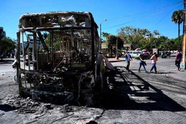 Texto original La gente camina cerca de un autobús quemado un día después de una protesta en demanda de la renuncia del presidente guatemalteco Alejandro Giammattei, en la Ciudad de Guatemala el 29 de noviembre de 2020. (Foto de JOHAN ORDONEZ / AFP a través de Getty Images)