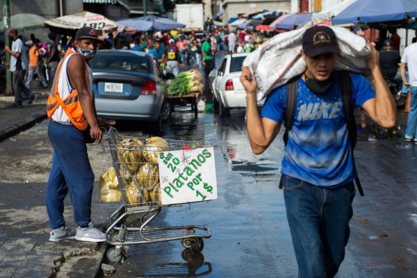 Un hombre (i) vende plátanos en el mercado municipal de Quinta Crespo Caracas (Venezuela), el 5 de diciembre de 2020, en medio de la pandemia de covid-19. (Foto de CRISTIAN HERNANDEZ / AFP a través de Getty Images)