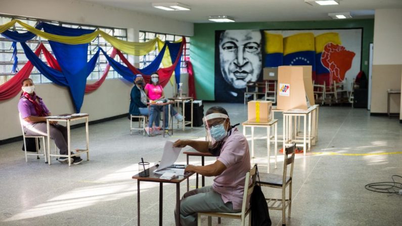 Los trabajadores electorales esperan a los votantes en una mesa de votación en una escuela en Caracas (Venezuela), el 6 de diciembre de 2020 durante las elecciones legislativas convocadas por el chavismo. (Foto de CRISTIAN HERNANDEZ / AFP a través de Getty Images)