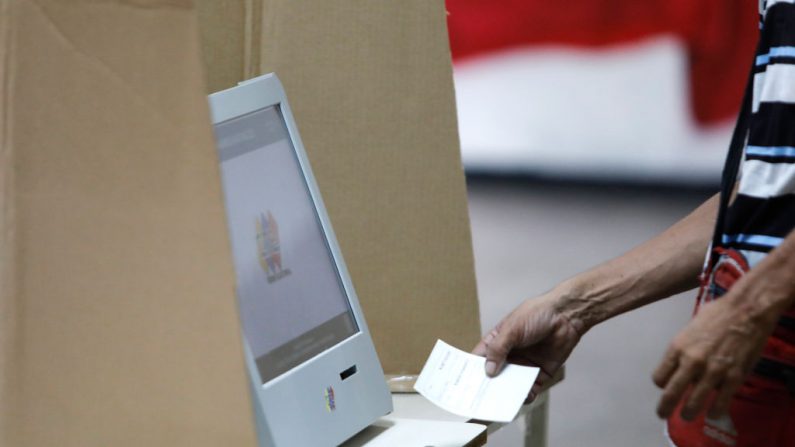 Un hombre toma la prueba de su voto de la máquina de votación en la Escuela Técnica Comercial Manuel Palacios Fajardo, el 6 de diciembre de 2020 en Caracas, Venezuela. (Leonardo Fernández Viloria/Getty Images)
