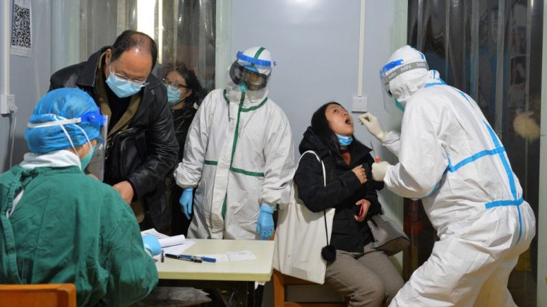 Esta foto tomada el 8 de diciembre de 2020 muestra a un trabajador de la salud realizando una prueba de ácido nucleico a un residente de Chengdu, en la provincia de Sichuan, al oeste de China, después de que se detectaran nuevos casos de covid-19 en la ciudad. (Foto de STR/AFP a través de Getty Images)