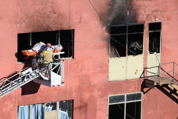 Los bomberos llevan un cadáver de un almacén donde vivían hasta 200 inmigrantes en condiciones miserables, el 10 de diciembre de 2020 en Badalona, cerca de Barcelona, un día después de que se produjera un incendio matando al menos a dos personas e hiriendo a 17. (Foto de LLUIS GENE / AFP a través de Getty Images)