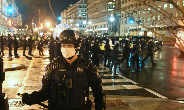 Un agente de policía con equipo antidisturbios hace guardia mientras varios manifestantes se reúnen cerca de la Black Lives Matter Plaza durante una protesta en Washington el 12 de diciembre de 2020. (Stephanie Keith/Getty Images)