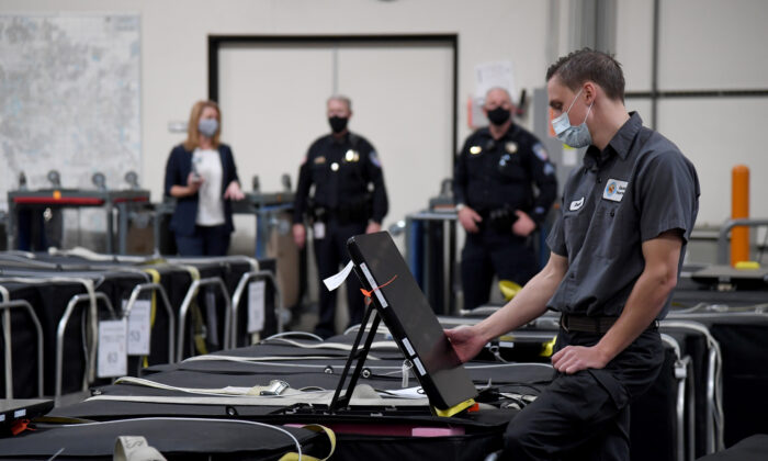 Un trabajador electoral del condado de Clark revisa una máquina de votación, entre otras, que están empaquetadas en el Departamento de Elecciones del condado de Clark en Las Vegas, Nevada, el 6 de noviembre. (Ethan Miller/Getty Images)