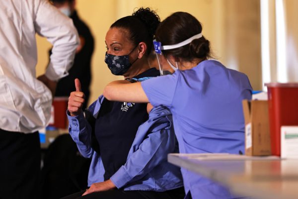 Un miembro de la oficina de EMS del Departamento de Bomberos de la ciudad de Nueva York levanta el pulgar mientras recibe la vacuna contra el COVID-19 en la Academia de Entrenamiento de Bomberos FDNY en Randall's Island el 23 de diciembre de 2020 en la ciudad de Nueva York. (Foto de Michael M. Santiago / Getty Images)