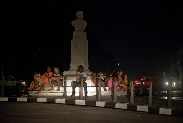 Cubanos sentados alrededor de un monumento junto a los faros de un automóvil durante un apagón en La Habana (Cuba) el 9 de septiembre de 2012. (Foto de ADALBERTO ROQUE / AFP / Getty Images)