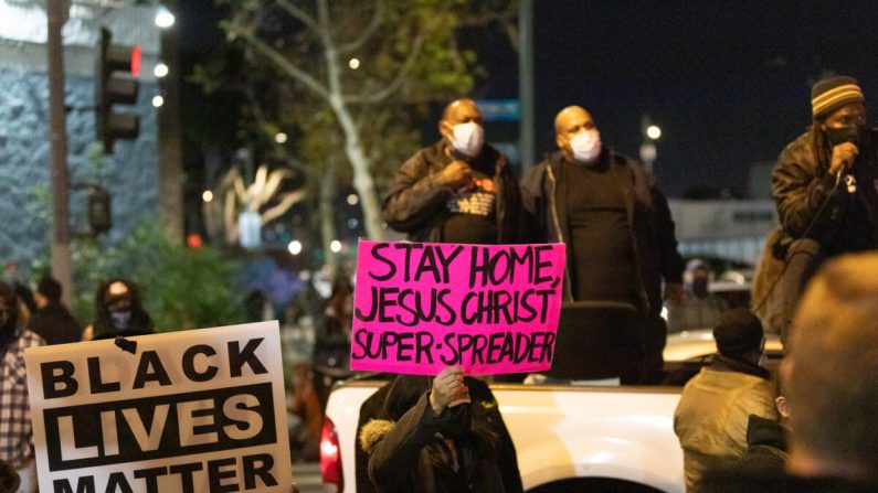 Los manifestantes sostienen carteles que protestan por un evento cristiano para personas sin hogar mientras bloquean el tráfico en Skid Row en Los Ángeles el 30 de diciembre de 2020. (John Fredricks/The Epoch Times)