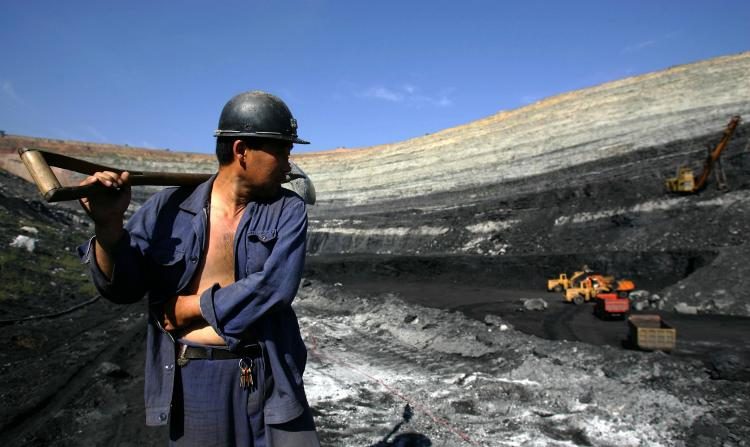 Un minero de carbón camina sobre vetas de carbón en una mina a cielo abierto en Chifeng de la Región Autónoma de Mongolia Interior, China, el 19 de agosto de 2006. (Fotos de China/Getty Images)
