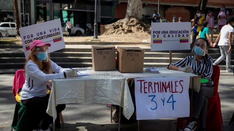 Voluntarios esperan votantes en una mesa durante la jornada de votación presencial de la consulta popular impulsada por el opositor Juan Guaidó el 12 de diciembre de 2020 en Caracas (Venezuela). EFE/RAYNER PEÑA R.