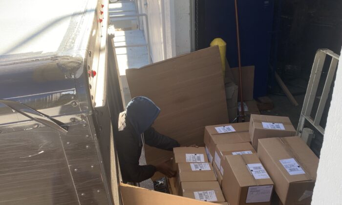 Un hombre recoge una caja con materiales electorales antes de colocarla en un camión de UPS en el almacén del secretario de Estado de Georgia en Atlanta, Georgia, el 2 de diciembre de 2020. (Ivan Pentchoukov/Epoch Times)