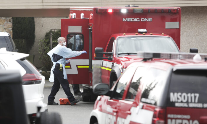 Personal de una ambulancia se prepara para transportar a un paciente de la residencia del Centro de Cuidados de la Vida donde algunos pacientes murieron de COVID-19, en Kirkland, Wash., el 5 de marzo de 2020.  (Jason Redmond/AFP vía Getty Images)