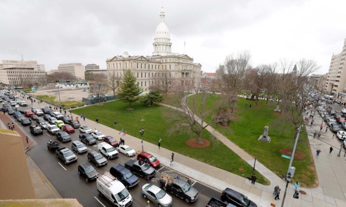El Capitolio del estado de Michigan se ve al fondo, mientras la gente en los vehículos protestan por las órdenes de cierre, en Lansing, Mich., el 15 de abril de 2020. (Jeff Kowalsky/AFP vía Getty Images)