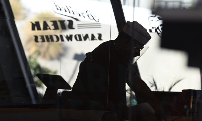 Camareros limpian las mesas dentro de un autocine después de que el condado de Los Ángeles prohibiera las comidas al aire libre, en West Hollywood, California, el 30 de noviembre de 2020. (Robyn Beck/AFP a través de Getty Images)