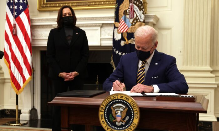 El presidente Joe Biden firma una orden ejecutiva, junto a la vicepresidenta Kamala Harris, durante un evento sobre la crisis económica, en el Comedor Estatal de la Casa Blanca, el 22 de enero de 2021. (Alex Wong/Getty Images)