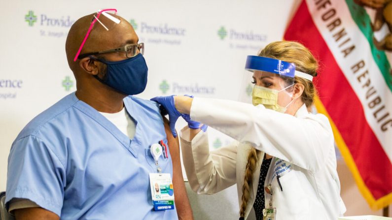 El enfermero registrado Michael Lowman (izq.) recibe la primera inyección de la vacuna de Pfizer contra el COVID-19 en el condado de Orange en el Hospital St. Joseph en Orange, California, el 16 de diciembre de 2020 (John Fredricks/The Epoch Times)