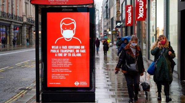 Un letrero que informa a las personas que deben llevar mascarilla en el transporte público o enfrentar una multa se muestra en Oxfrord Street en Londres el 14 de enero de 2021 durante el tercer cierre del covid-19 en Gran Bretaña. (Foto de Niklas Halle'n / AFP a través de Getty Images)