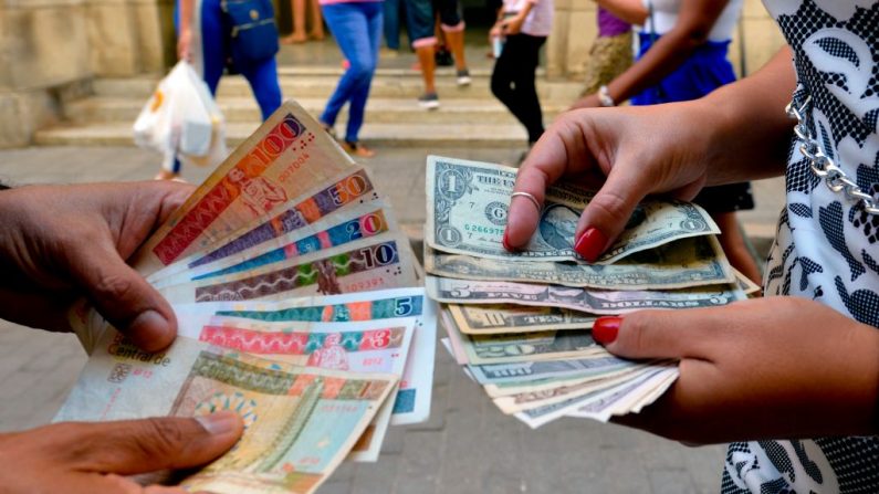 Cubanos muestran CUC y billetes de dólar en la calle de La Habana (Cuba), el 10 de diciembre de 2019. (Yamil Lage/ AFP vía Getty Images)