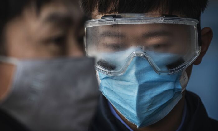 Un trabajador de los ferrocarriles chinos empaña las gafas de seguridad mientras espera para comprobar la temperatura de los pasajeros que llegan a una estación de tren en Beijing, el 31 de enero de 2020. (Kevin Frayer/Getty Images)
