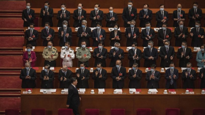 El líder chino Xi Jinping (abajo) llega a la sesión de clausura de la conferencia de la legislatura títere del régimen chino mientras otros funcionarios del Partido Comunista aplauden, en Beijing, el 28 de mayo de 2020. (Kevin Frayer/Getty Images)