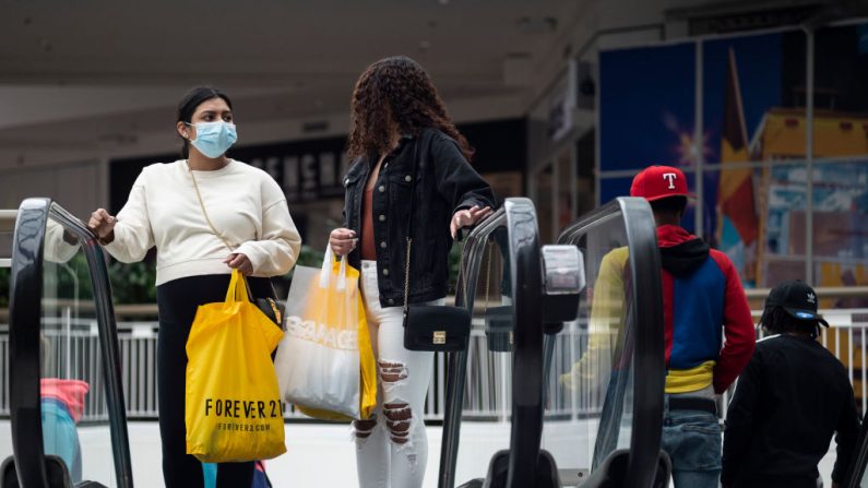 La gente sostiene sus bolsas de compras en una escalera mecánica en el Mall of America el 10 de junio de 2020 en Minneapolis, Minnesota, EE.UU. en medio de la pandemia de covid-19. (Foto de Stephen Maturen / Getty Images)