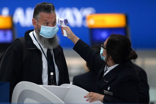 Se toma la temperatura a un pasajero en un mostrador de facturación de British Airways en el aeropuerto de Heathrow, al oeste de Londres, Reino Unido, el 10 de julio de 2020. (Foto de Daniel Leal-Olivas / AFP vía Getty Images)