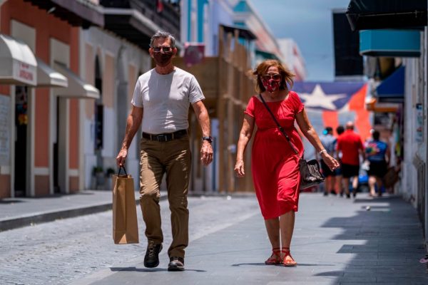 Turistas con mascarillas caminan por una calle del Viejo San Juan, Puerto Rico el 20 de julio de 2020. (Foto de Ricardo Arduengo / AFP vía Getty Images)