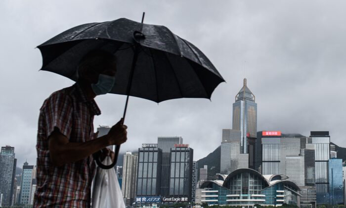 Un hombre usa su paraguas en el paseo marítimo de Tsim Sha Tsui, de Kowloon, frente al puerto de Victoria, el 19 de agosto de 2020. (Anthony Wallace/AFP a través de Getty Images)