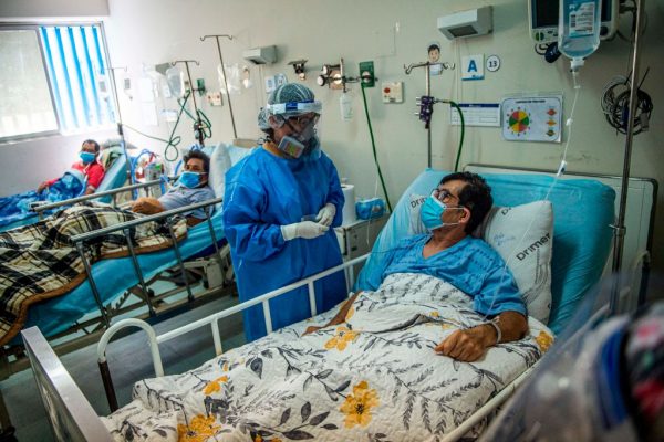 Una profesional de la salud atiende a un paciente con COVID-19 en la Unidad de Cuidados Intensivos del Hospital Alberto Sabogal Sologuren, en Lima, Perú, el 11 de diciembre de 2020, en medio de la nueva pandemia de covid-19. (Foto de ERNESTO BENAVIDES / AFP a través de Getty Images)
