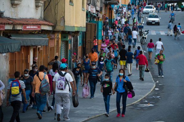 Personas con mascarillas caminan por una calle del vecino Petare en Caracas, Venezuela, el 21 de diciembre de 2020, en medio de la nueva pandemia de covid-19. (Foto de Cristian Hernandez / AFP a través de Getty Images)