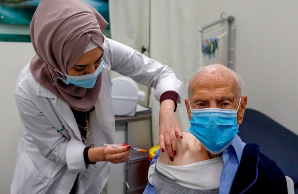 Una trabajadora de la salud administra una vacuna contra el COVID-19 a un anciano en los Servicios de Salud de Clalit en el barrio palestino de Beit Hanina, en el este de Jerusalén, anexado por Israel, el 7 de enero de 2021. ( Foto de AHMAD GHARABLI / AFP a través de Getty Images)