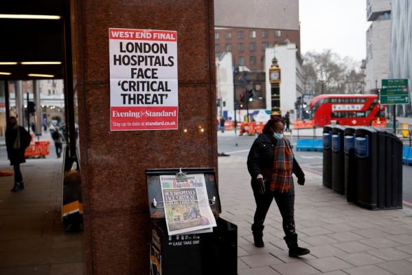 Una peatona con una mascarilla pasa frente a un puesto de los periódicos Evening Standard en el centro de Londres, el 8 de enero de 2021, cuando Inglaterra ingresó a un tercer bloqueo debido al covid-19. (Foto de TOLGA AKMEN / AFP a través de Getty Images)