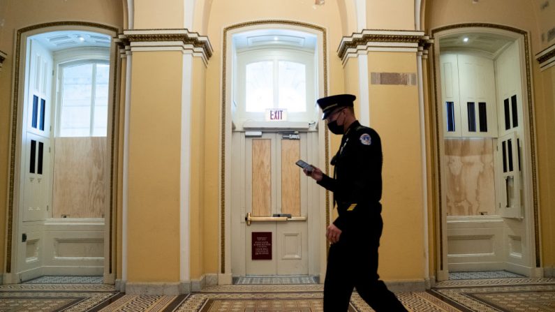 Un oficial de policía del Capitolio pasa junto a las ventanas tapiadas en el Capitolio de los Estados Unidos el 11 de enero de 2021 en Washington, DC. (Stefani Reynolds/Getty Images)