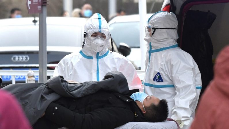 Trabajadores médicos con trajes de protección como precaución contra el virus del PCCh trasladan a un paciente a un hospital de Beijing el 13 de enero de 2021. (GREG BAKER/AFP vía Getty Images)
