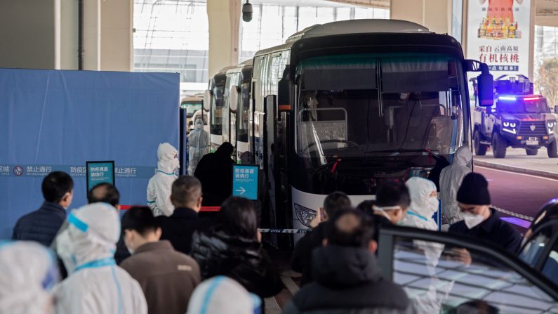 Los miembros del equipo de la Organización Mundial de la Salud (OMS) que investigan los orígenes de la pandemia del Covid-19 suben a un autobús luego de su llegada al aeropuerto de Wuhan el 14 de enero de 2021. (NICOLAS ASFOURI/AFP a través de Getty Images)
