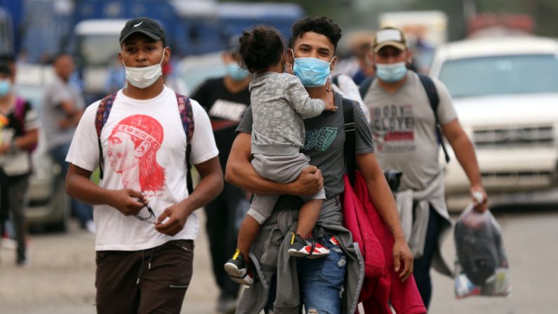 Un padre carga a su hija mientras comienzan su viaje hacia la frontera guatemalteca como parte de una caravana de migrantes el 15 de enero de 2021 en San Pedro Sula, Honduras. (Foto de Milo Espinoza / Getty Images)