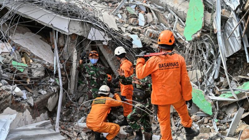 Los equipos de rescate intentan sacar el cuerpo de una víctima del terremoto atrapada en un edificio derrumbado en Mamuju el 16 de enero de 2021, un día después de que un terremoto de magnitud 6.2 sacudiera la isla indonesia de Sulawesi. (Foto de Hariandi Hafid / AFP a través de Getty Images)